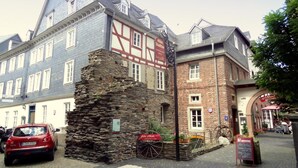 Um edifício histórico com base de pedra e estrutura de madeira, apresentando uma placa com o nome 'Altes Stadttor Hotel'.