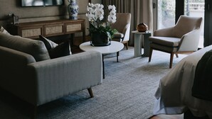 Una habitación de hotel moderna con una cama grande, un sofá, una mesa de centro y un televisor montado en la pared.