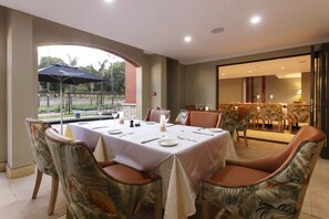 A dining area with a table set for four, surrounded by chairs with a tropical leaf pattern.