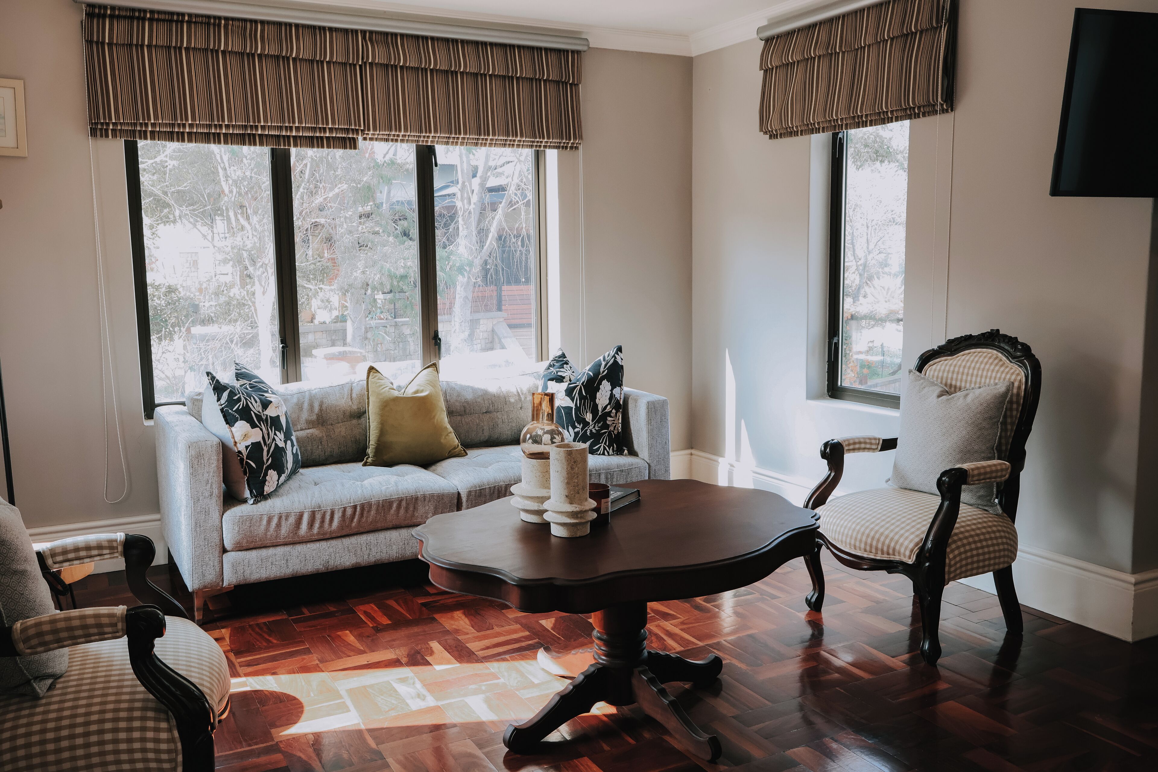 Una sala de estar con un sofá modular, una mesa de centro redonda y un sillón clásico.