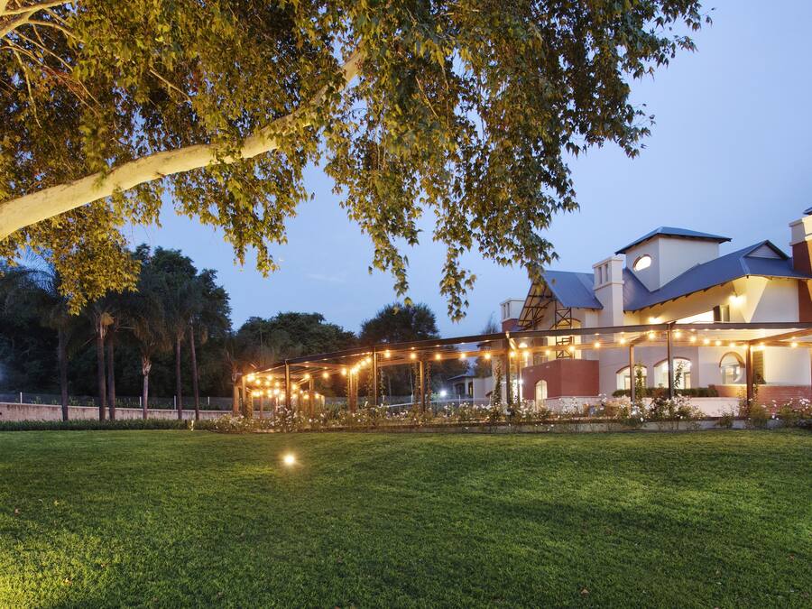 A church with a large tree in the foreground and a covered outdoor area with string lights.
