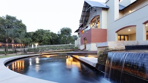 Un edificio moderno con una cascada, muros de piedra y un área pavimentada.