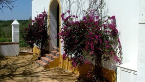A white building with a yellow door and steps leading to an arched entrance. - El Garrotal Rural Cottage (Sevilla)