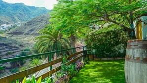 Un jardin luxuriant, agrémenté d’une clôture en bois, d’une barrique en bois et offrant une vue sur un paysage vallonné.
