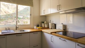 Une cuisine moderne dotée d’une grande fenêtre, d’appareils électroménagers en acier inoxydable et d’un plan de travail en bois.