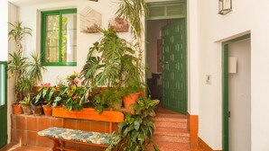 Un escalier agrémenté de plantes en pot, un banc et une porte verte.