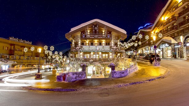 Un hôtel enneigé, avec une enseigne indiquant « Courchevel Tourisme » et, au fond, une autre enseigne indiquant « Hôtel Les Tovets ».