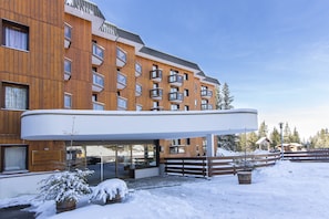 Un hôtel à plusieurs étages, doté d’une façade en bois, de balcons et d’une entrée couverte.
