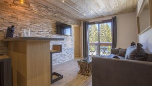 Un salon moderne avec un plafond en bois, un mur en pierre, un téléviseur à écran plat, un meuble en bois, une table basse en verre et un canapé.