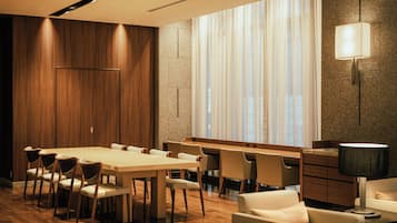 Una sala de conferències moderna amb una taula llarga, cadires, un sofà i una làmpada.