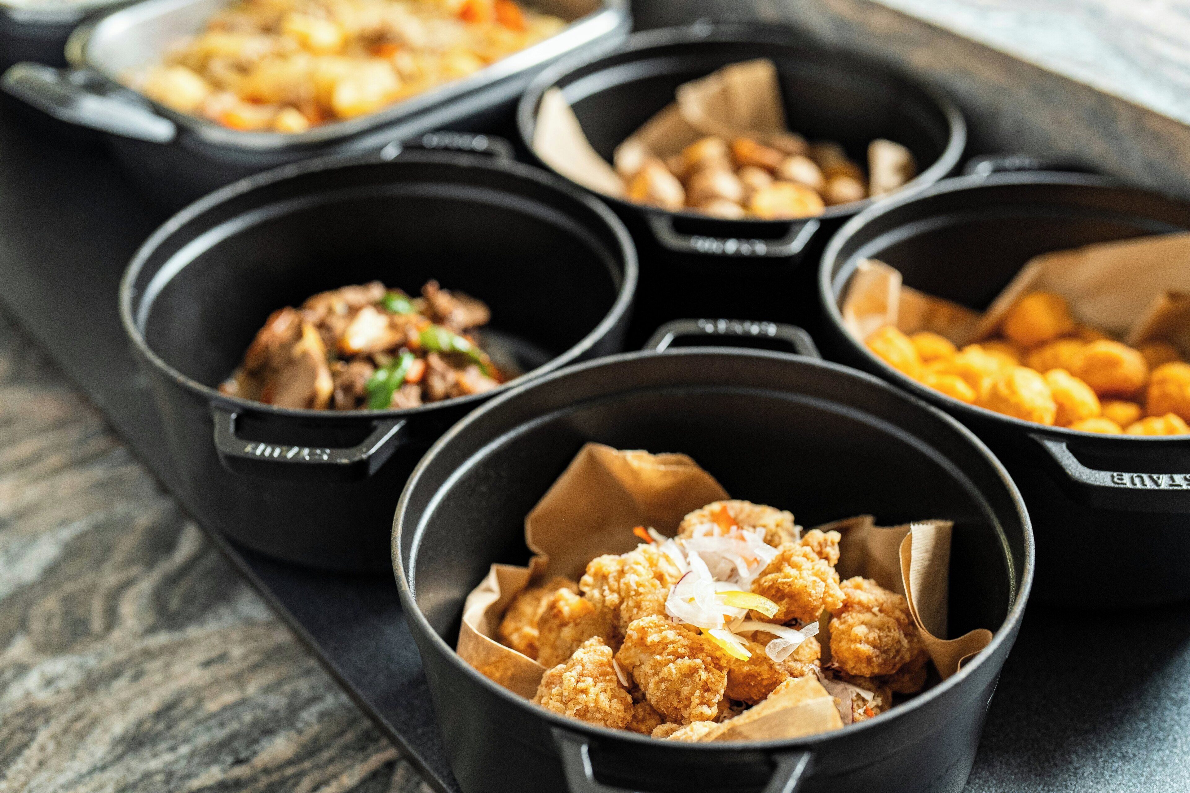A tray with multiple black bowls containing various food items.