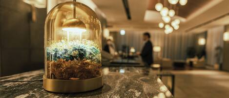 Una cúpula de cristal con luz en su interior, sobre una superficie de mármol en el vestíbulo de un hotel.