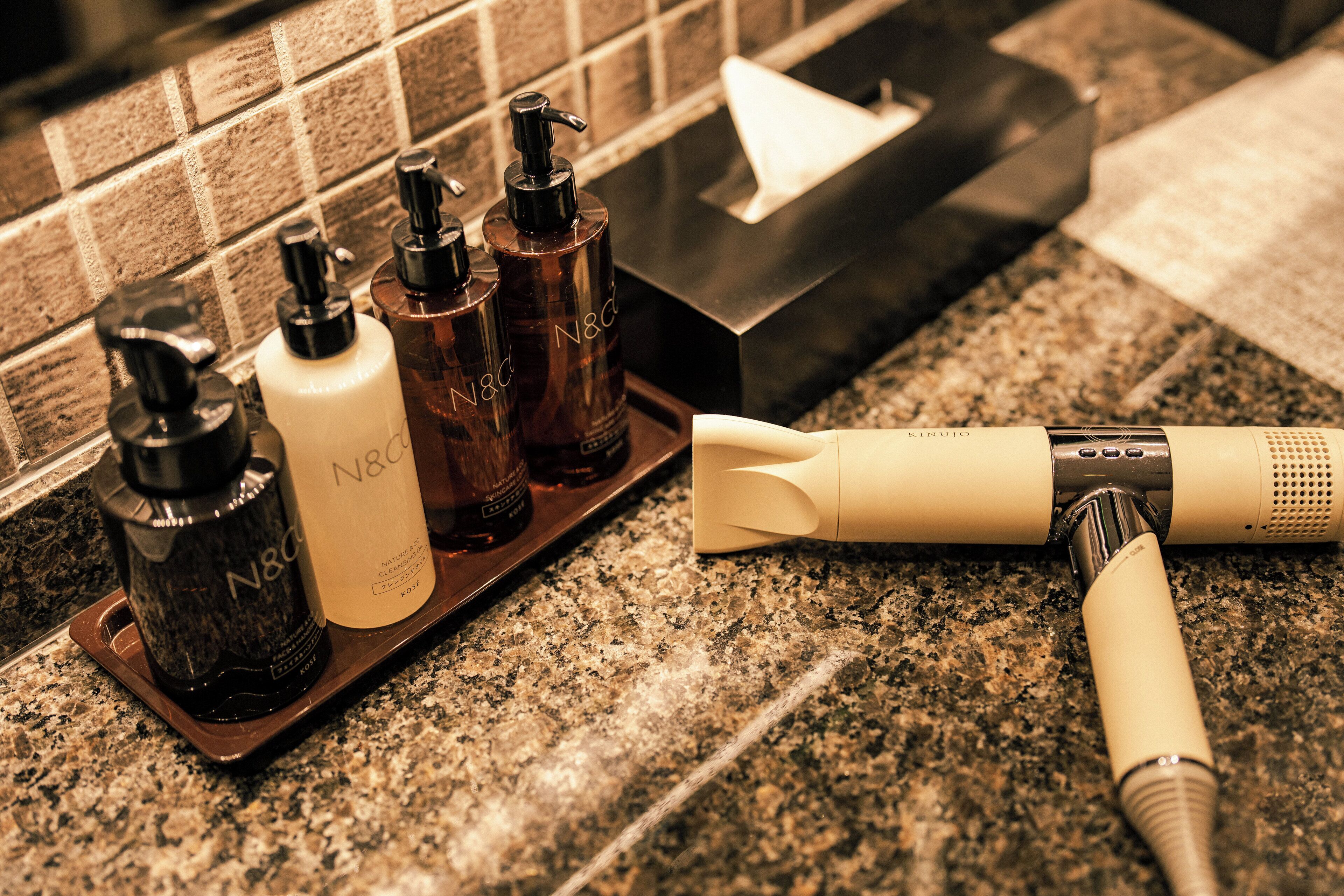 A bathroom counter with various toiletries, including bottles and a hairdryer.