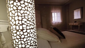 Ein Schlafzimmer mit einem Bett, einem Nachttisch, einer Lampe und einem Fenster.