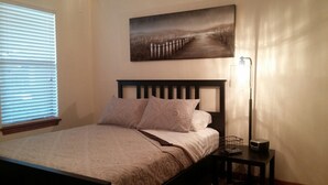 Ein Schlafzimmer mit Bett, Nachttisch, Lampe und einem Bild an der Wand.