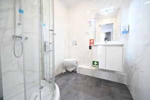 A modern bathroom with a glass-enclosed shower, a toilet, and a sink with a mirror. - Famous Crows Lisbon Suites (Lisbon)