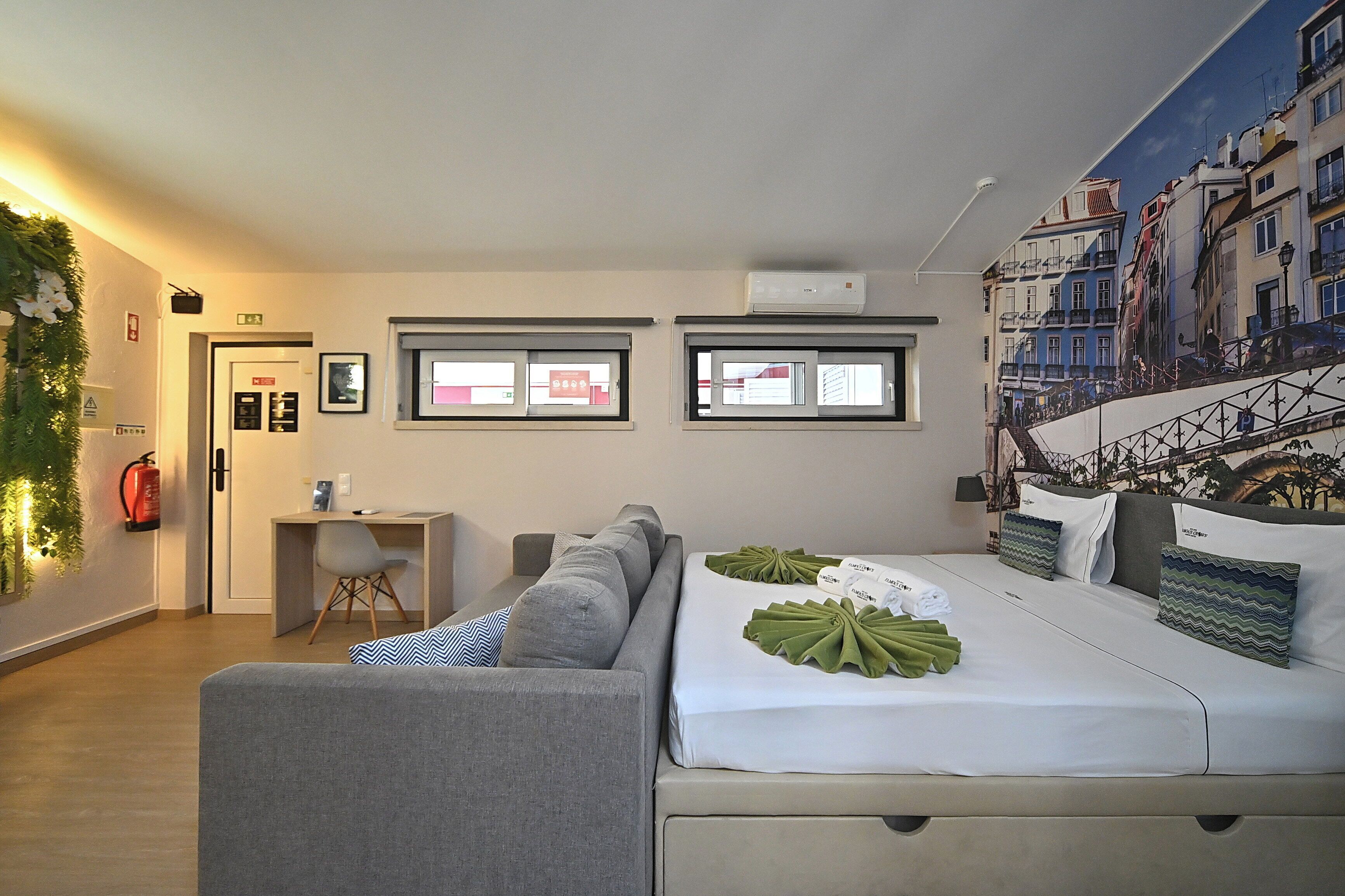 Habitación de hotel con cama, escritorio, silla y vista panorámica de la ciudad a través de las ventanas.