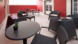 A covered outdoor seating area with wicker furniture and a potted orchid. - Famous Crows Lisbon Suites (Lisbon)