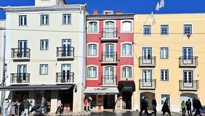 A row of colorful buildings with balconies, storefronts, and pedestrians. - Famous Crows Lisbon Suites (Lisbon)