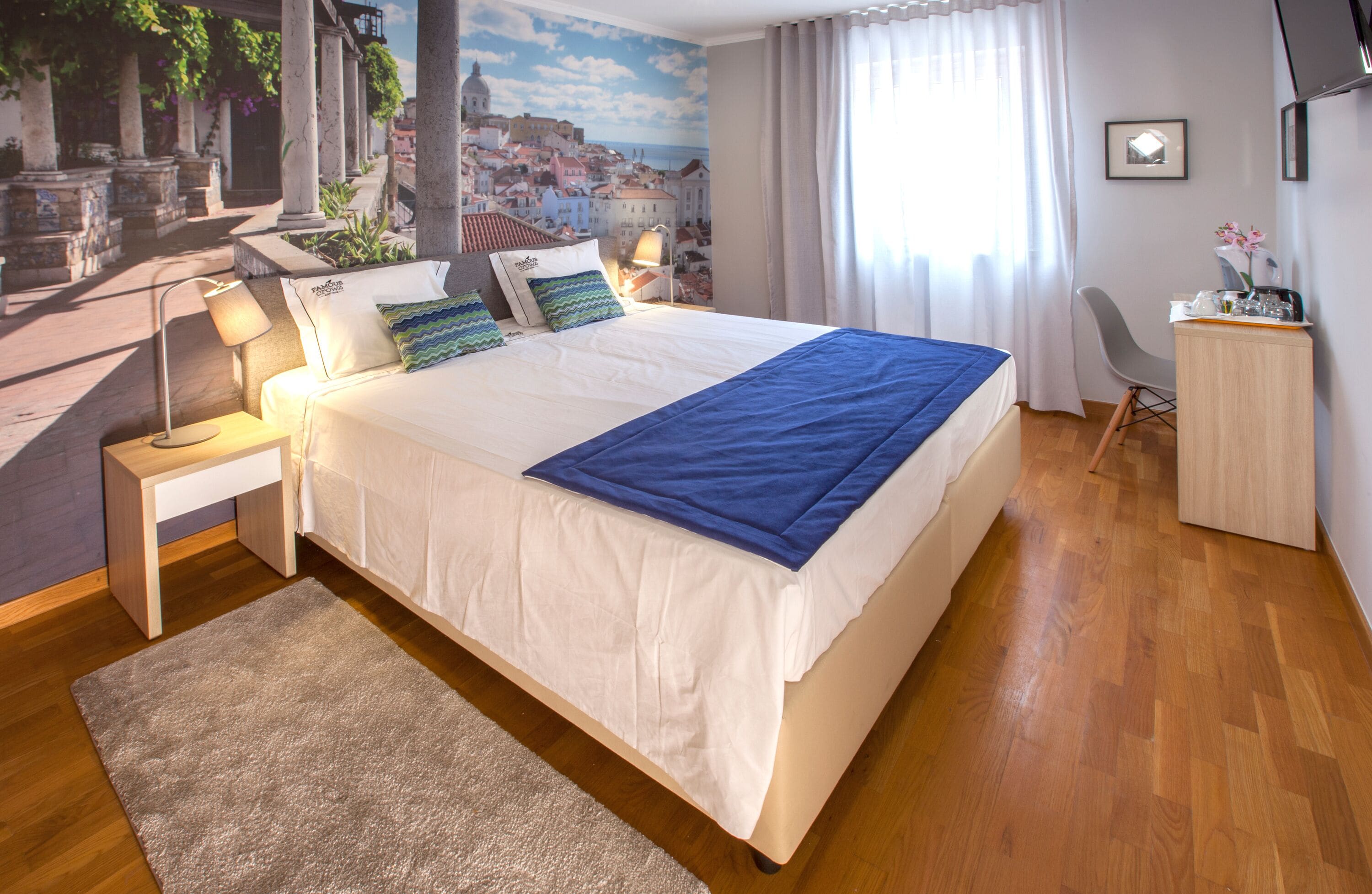 A hotel room with a large bed, a nightstand with a lamp, a desk, and a chair.