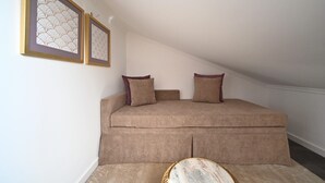 A bedroom with a sofa bed, two pillows, a small round table, and two framed pictures on the wall. - Famous Crows Lisbon Suites (Lisbon)