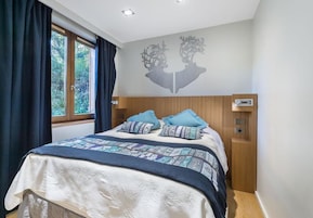 Un dormitorio con cama, cortinas, una ventana y un adorno en la pared.