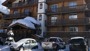 Un hotel de varios pisos con balcones de madera y tejados nevados.