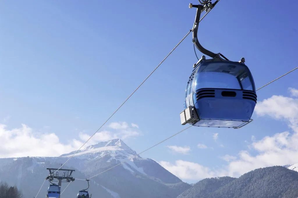 A cable car system with a clear sky and a snow-capped mountain in the background.