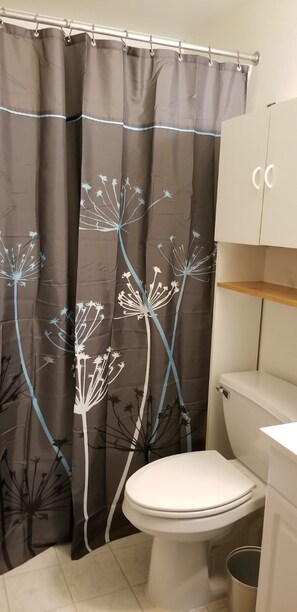 A bathroom with a toilet, a cabinet, and a shower curtain with a floral pattern.