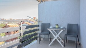 A balcony with a table and two chairs, a potted plant, and a view of buildings. - Perfect apartment for 3 with terrace/wifi/pet-friendly (Fazana)