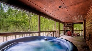A hot tub in a wooden cabin with a view of a forest.
