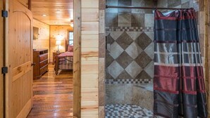 A wooden interior with a checkered floor, a metal bed frame, and a tiled shower area.