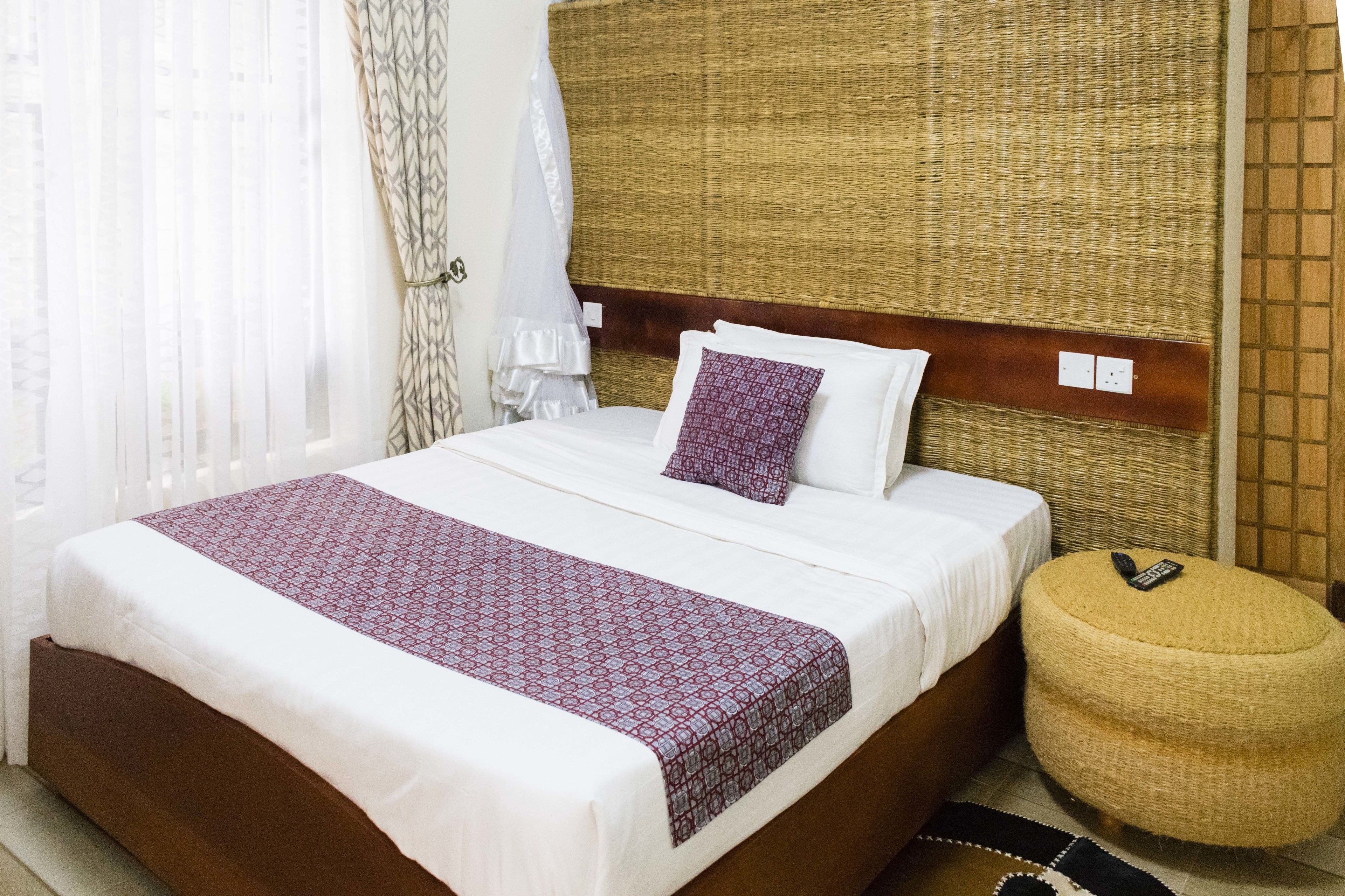 Una cama bien hecha con una colcha estampada, una almohada y una mesita de noche con un control remoto.