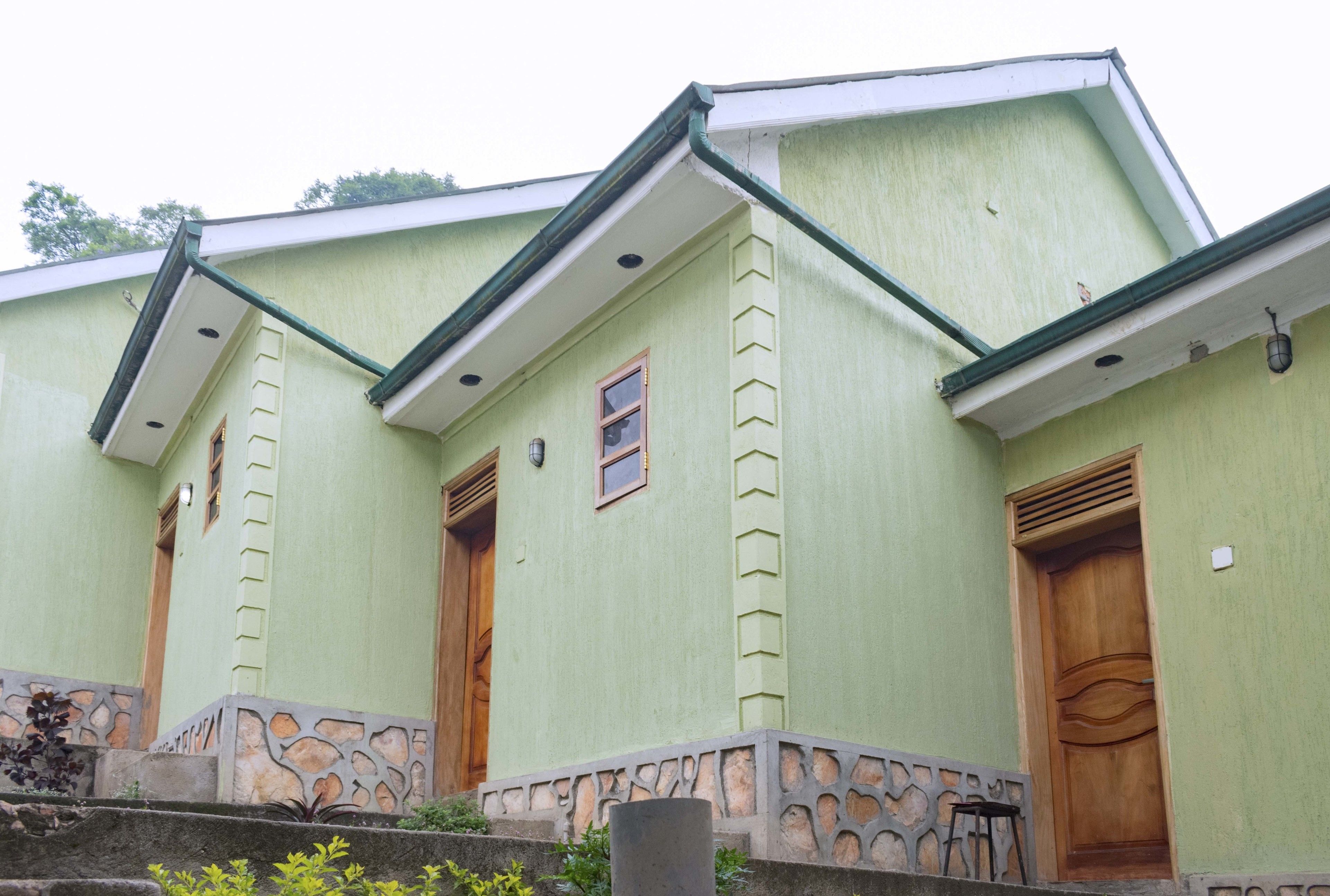 A building with a green exterior, two wooden doors, and a stone base.