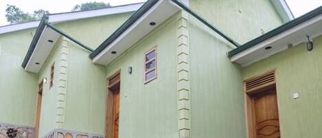A building with a green exterior, two wooden doors, and a stone base.