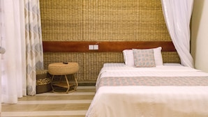 A bedroom with a woven headboard, a bed with patterned bedding, a small round stool, and a woven basket. - Tooro Fairway Hotel (Fort Portal)