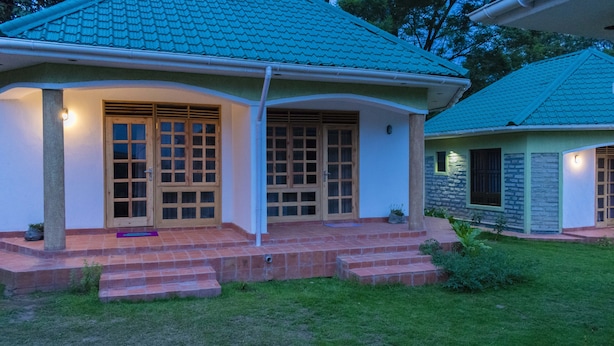 A house with a green roof, a porch with steps, and a small garden. - Tooro Fairway Hotel (Fort Portal)