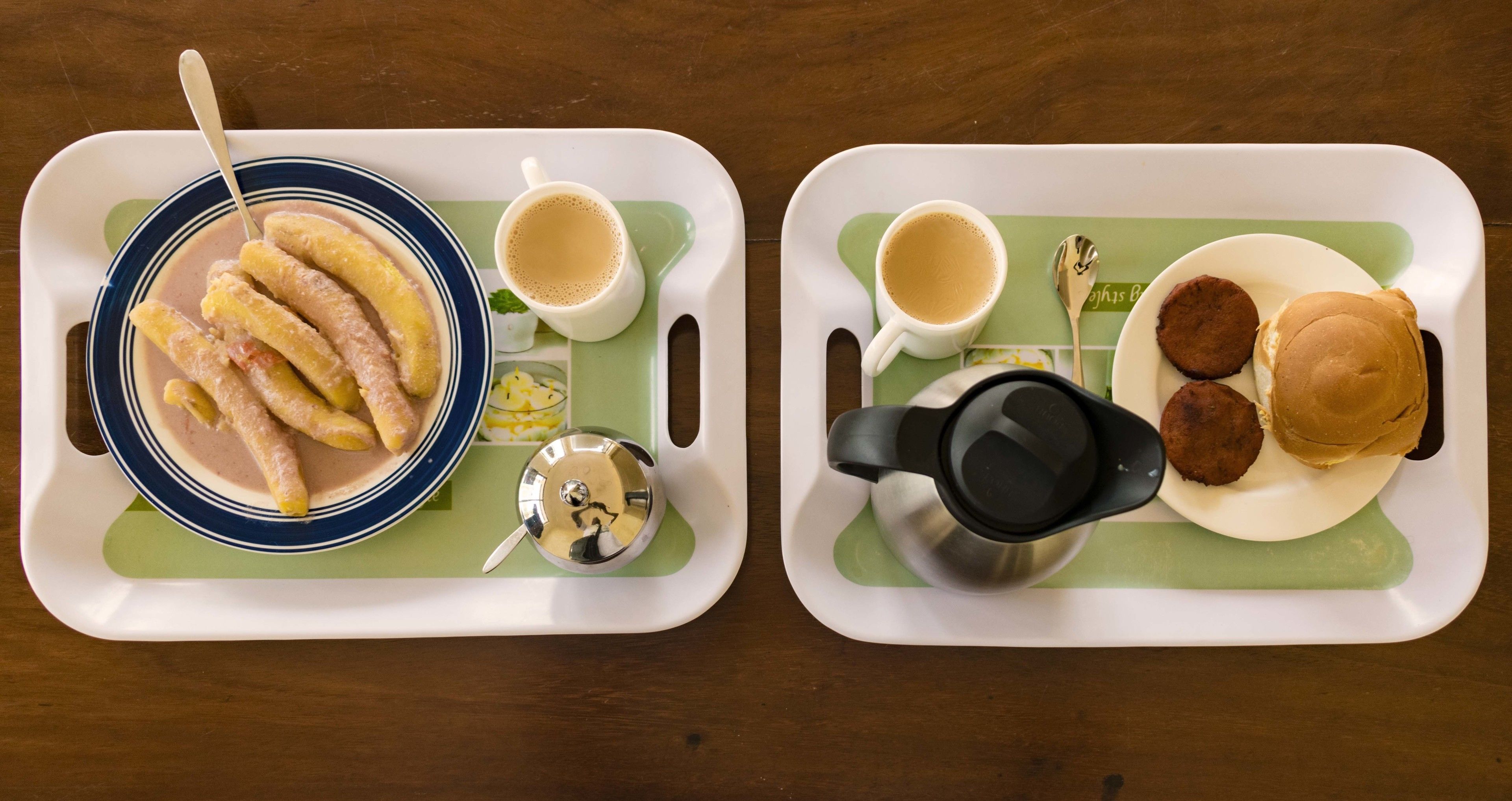 Due vassoi con cibo e bevande, tra cui un piatto di fritture, una tazza di caffè e una bevanda calda.