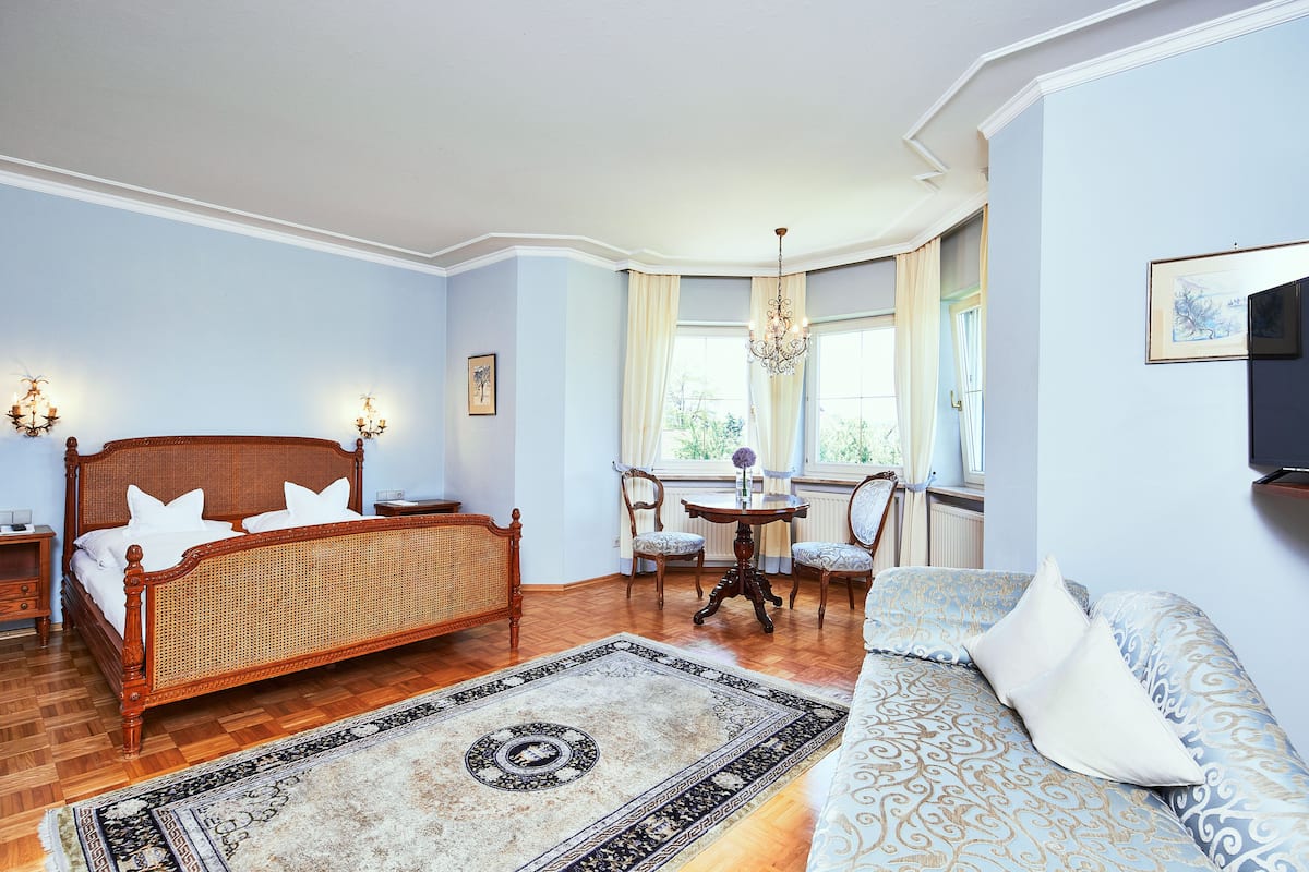 Une chambre à coucher avec un lit en bois, un canapé, une table à manger avec des chaises et un lustre.