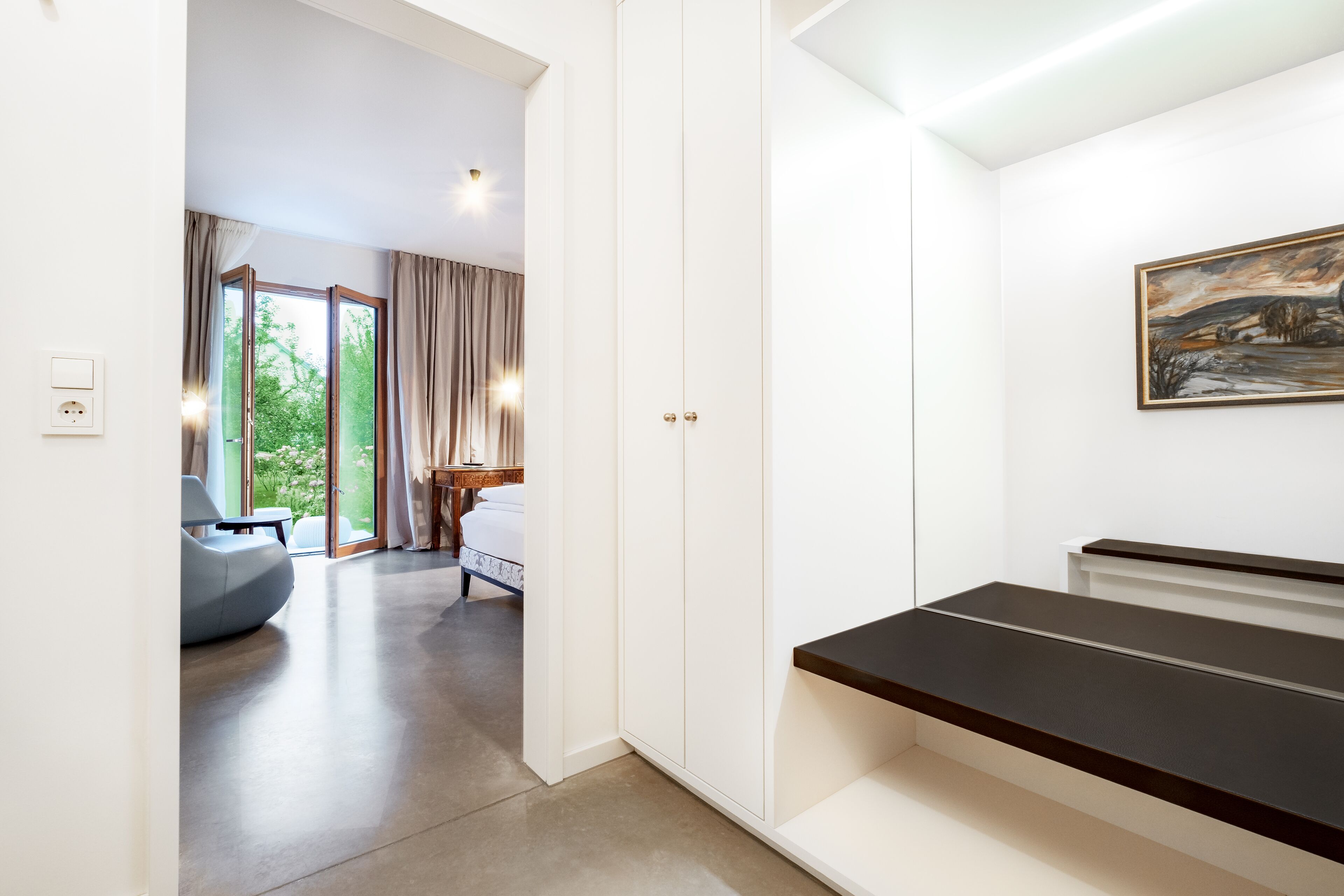 A modern hotel room with a large bed, a desk, and a view of the outdoors.