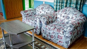 Un saló amb un sofà estampat, una taula auxiliar de metall i un camí de taula amb dibuixos.