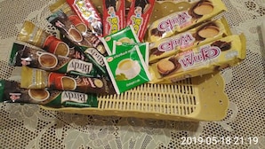 A tray of assorted snacks and beverages on a lace tablecloth.