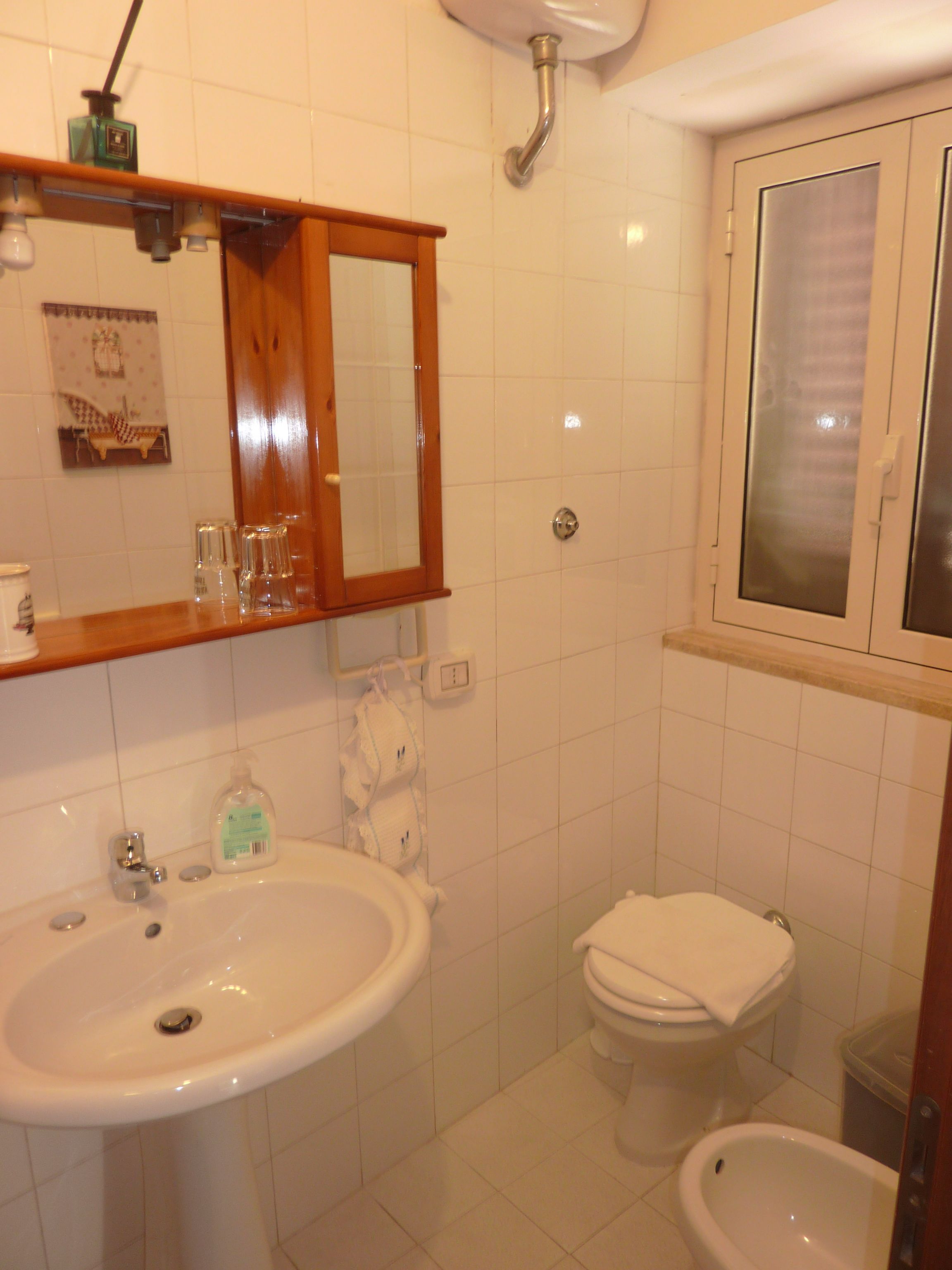 Un baño con lavamanos, espejo, inodoro, bidé y ventana.