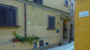 A narrow street with a yellow building, shutters, and a sign reading "VIA PATRICOLO". - Duomo Rent Room & Flat (Agrigento)