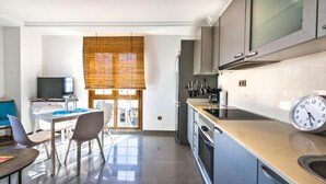 Una cocina moderna con comedor, televisión y reloj.