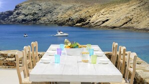 Une table à manger, avec ses chaises, donnant sur la mer et offrant une vue sur les bateaux.