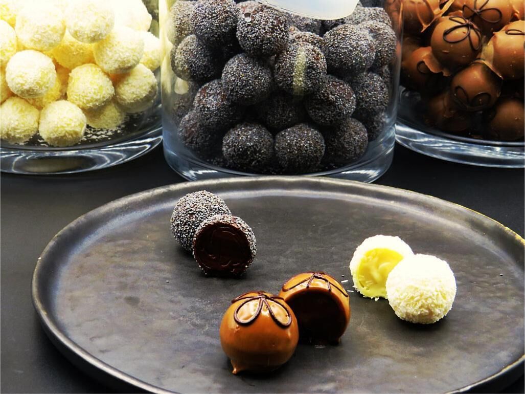 A variety of chocolate truffles in different colors and textures on a plate.