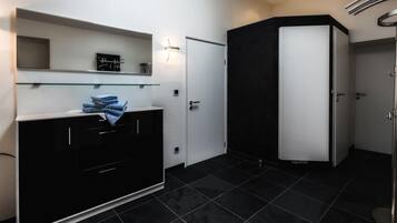 A modern bathroom with black and white cabinetry, a glass shelf, and a black tiled floor.