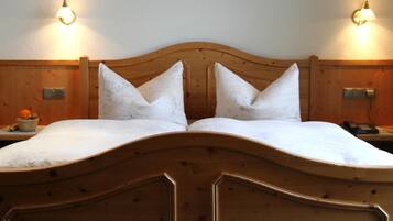 A double bed with a wooden headboard, two bedside tables with lamps, and a fruit bowl on the left side.