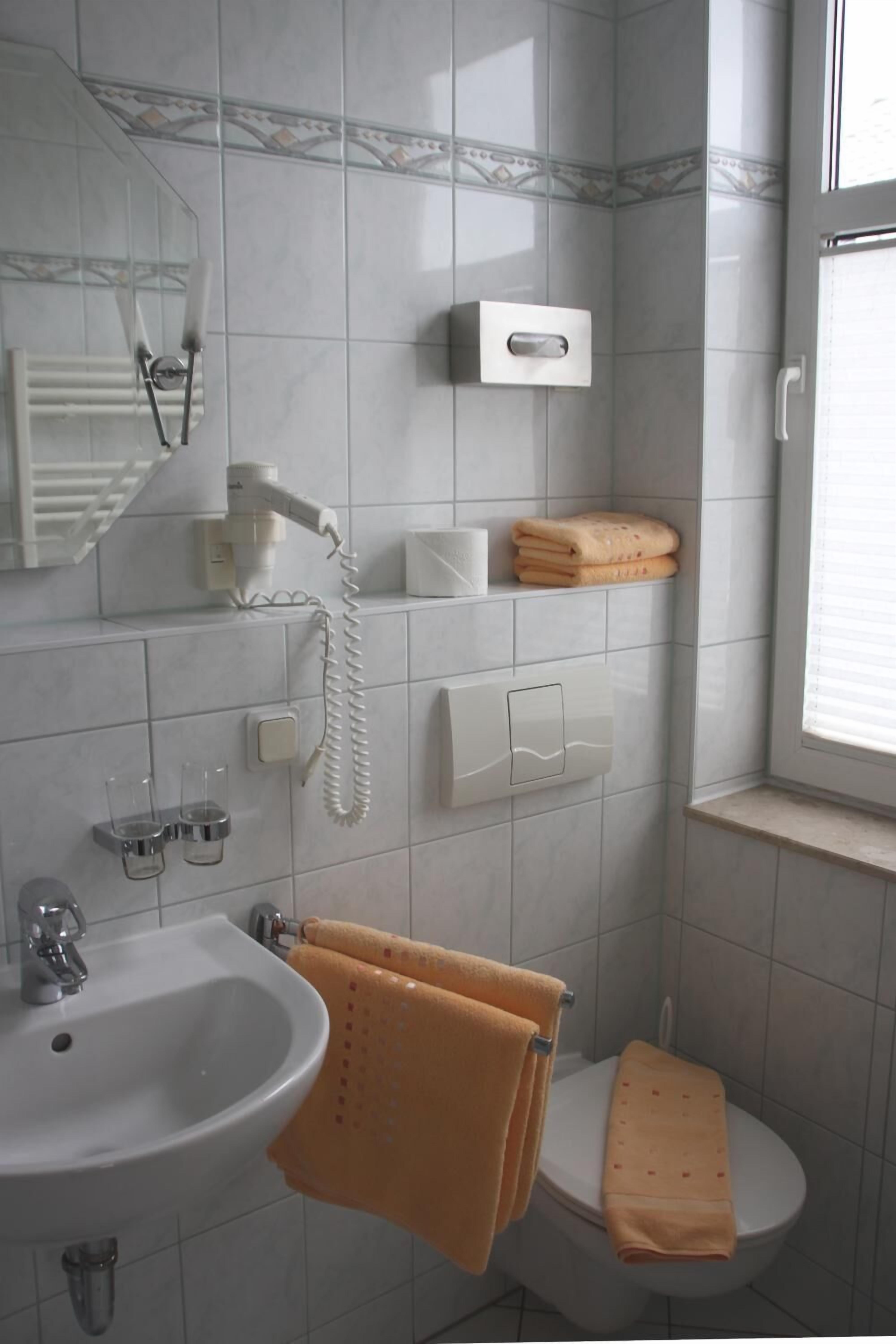 A bathroom with a sink, toilet, and a towel rack with towels.